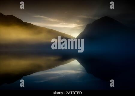 Morgennebel steigt um Buttermere, den See im englischen Lake District in Nordwestengland. Das angrenzende Dorf Buttermere hat seinen Namen Stockfoto