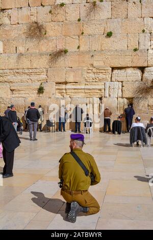 Ein bewaffneter Soldat in Jerusalem, Israel, beugt sich an einem sonnigen Tag vor der westlichen Mauer, der heiligsten Stätte für das judentum. Juden beten an der Klagemauer Stockfoto