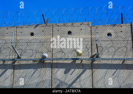 Ein Nahbereich der Trennmauer zwischen Israel und Palästina. Zwei Bälle von Kindern im Westjordanland verfingen sich im Stacheldraht und Zaun. Ein Symbol von d Stockfoto