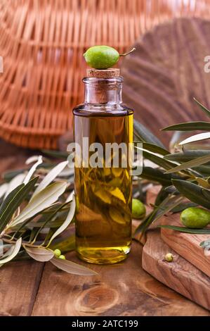 Grüne Oliven in Blechdosen mit Laib frisches Brot und junge Oliven Zweig, eine Flasche Olivenöl auf Lehm board über alte Holz Hintergrund. Platz für Text Stockfoto