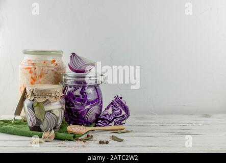 Drei Glasgefäße aus fermentiertem Weiß, Rotkohl, Zwiebeln. Gemüse auf hellem Hintergrund. Mit Textilgrün. Fermentation ist eine Quelle von Probiotikum Stockfoto