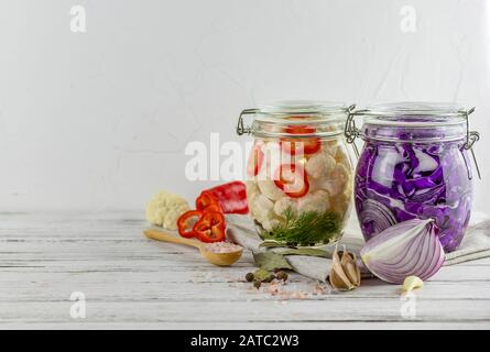 Zwei Glasgefäße aus fermentiertem Rotkohl, Blumenkohl, Gemüse auf hellem Hintergrund, mit hellgrauem Textil. Fermentation ist eine Quelle von Probioti Stockfoto