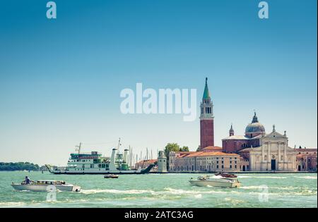 Venedig am sonnigen Sommertag, Italien. Motorboote fahren an der Insel San Giorgio Maggiore in Venedig vorbei. Blick auf die Lagune in Venedig mit blauem Himmel für Backgroschen Stockfoto