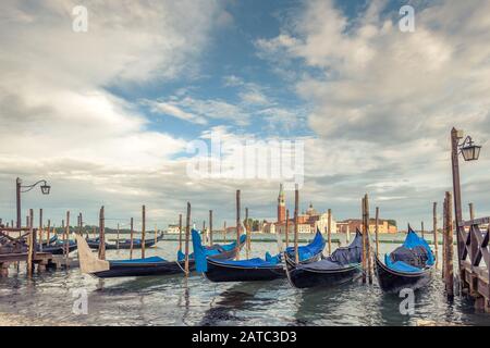 Pier mit Gondeln in der Nähe des Markusplatzes in Venedig, Italien. Die Gondel ist ein traditioneller romantischer Transport in Venedig. San Giorgio Maggiore im B. Stockfoto