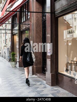 Brüsseler Altstadt / Belgien - 06 07 2019: Stilvoll schöne Frau in schwarzem Kleid, die durch die gehobene Einkaufsstraße Dansaert geht Stockfoto