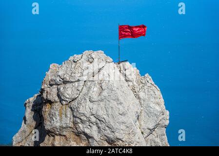 Der Felsen auf dem Berg Ai-Petri mit roter Flagge über dem Schwarzen Meer auf der Krim, Russland. Ai-Petri ist eines der höchsten Berge der Krim und Touristenattraktion Stockfoto