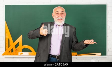 Spüren Sie den Erfolg. Trigonometrie-Lektion im Klassenzimmer. Lernen Sie hier. Lehrer für leitende Männer verwenden mathematische Werkzeuge. Bärtiger Dozent erklärt Geometrie auf der Tafel. Zurück zur Schule. Mathematische Grafikwerkzeuge. Stockfoto