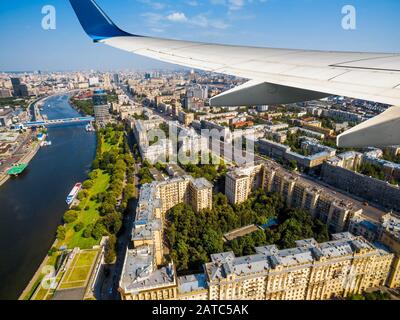 Flugzeug fliegt über Moskau, Russland. Luftpanorama vom Flugzeugfenster aus über die Moskauer Stadt und den Moskwa-Fluss. Der Flügel des Flugzeugs über dem Kutusowski Prospek Stockfoto