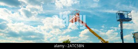 Kirschpflücker auf blauem Himmel Hintergrund. Ausleger mit Hubeimern schwerer Maschinen. Panoramablick auf die Bahnsteige der Teleskop-Aufzüge Stockfoto