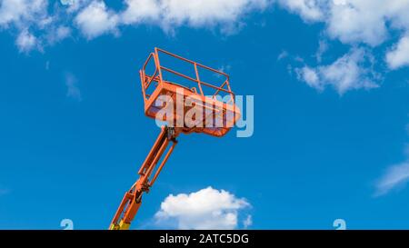 Kirschpflücker auf blauem Himmel Hintergrund. Ausleger mit Hubschaufel schwerer Maschinen. Orangefarbene Plattform des Teleskop-Aufzugs im Sommer. Stockfoto