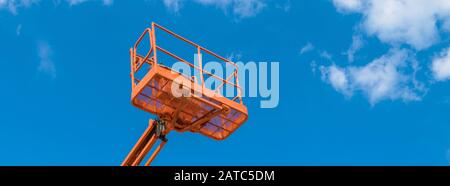 Kirschpflücker auf blauem Himmel Hintergrund. Ausleger mit Hubschaufel schwerer Maschinen. Plattform der Teleskopkonstruktion heben Nahaufnahme an. Stockfoto