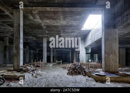 Betonkonstruktion des Untergeschosses eines großen Gebäudes. Panorama im Inneren der modernen Baustelle im Dunkeln. Zeitgenössische Struktur im Bau w Stockfoto