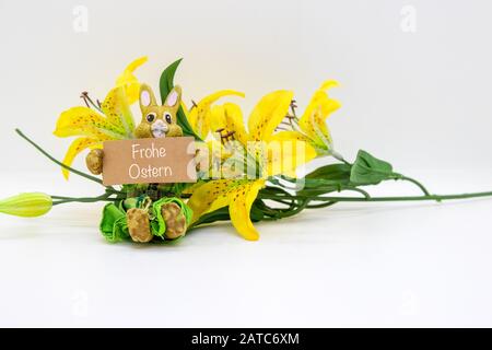 Frohe Ostern schrieb auf einem Schild, das von einem Hünenchen mit einer Blume gehalten wurde, die auf weißem Hintergrund isoliert war Stockfoto