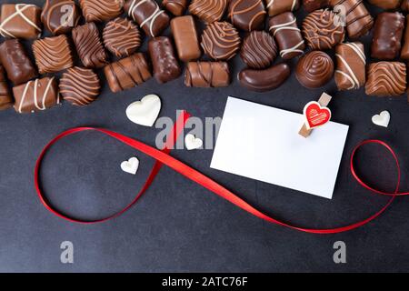 Pralinen mit weißer Karte für Valentinstag auf schwarzem Hintergrund Stockfoto