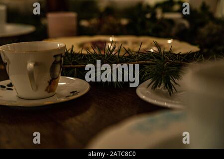 Schreibtisch voller Tassen und Teller mit einem Ast in der Mitte, verlegter Tisch zu Weihnachten Stockfoto