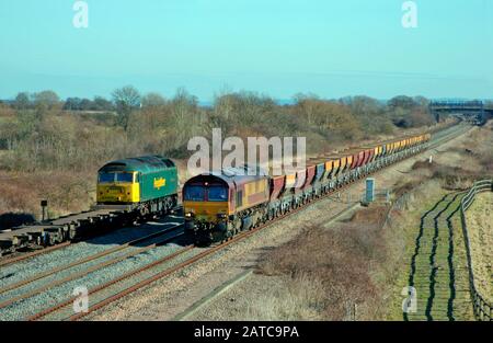 Ein Güterzugpaar, das von einer Klasse 57 Nummer 57011 und einer Klasse 66 Nummer 66141 gearbeitet wurde, fahren jeweils bei Denchworth auf der Great Western Mainline vorbei. Stockfoto