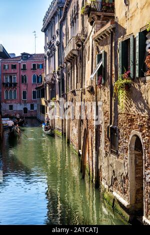 Venedig, Italien - 21. Mai 2017: Gondeln mit Touristen schweben entlang der alten schmalen Straße. Die Gondel ist der attraktivste Touristentransport Venedigs. Stockfoto