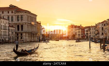 Venedig bei Sonnenuntergang, Italien. Gondel mit Touristen segelt nachts auf dem Canal Grande. Blick auf die Stadt Venedig bei Sonneneinstrahlung am Abend. Landschaft der sonnigen Straße in Stockfoto