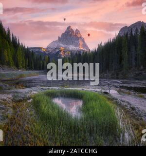 Heißluftballons, die bei Sonnenuntergang über den Bergen fliegen, Auronzo di Cadore, Belluno, Veneto, Italien Stockfoto