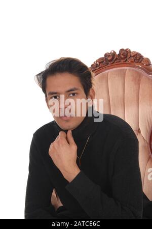 Ein Nahbild eines jungen, gut aussehenden Mannes in einem schwarzen Pullover, der in einem Sessel sitzt, isoliert für weißen Hintergrund Stockfoto