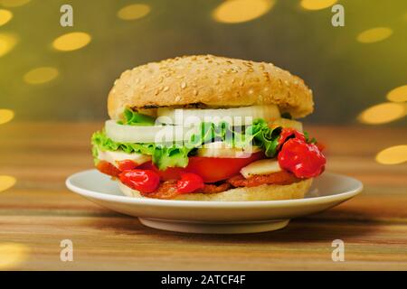 Hausgemachter Burger auf rustikalem Holzhintergrund. Köstlicher gegrillter Burger auf einem weißen Teller Stockfoto