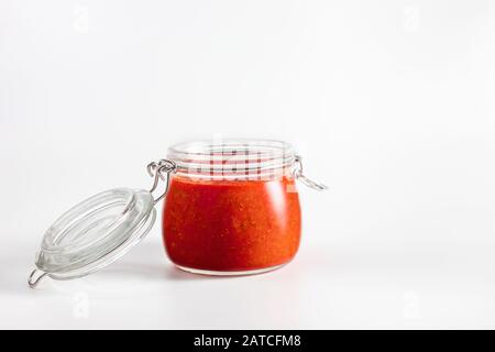 Heiße Chili Pfeffer Soße Paste Harissa. Adjika. Traditionelle Tunesien-Küche, georgische und arabische Küche. Hausgemachte Roseharissa in einem Glasbecher. Stockfoto