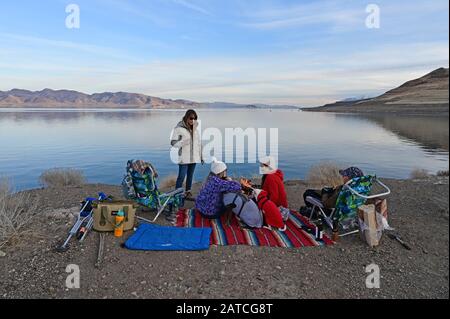Pyramid Lake, Reno, Nevada - 18. Januar 2020: Junge Frauen genießen einen ruhigen Nachmittag mit ihren Hunden auf Felsformation mit Blick auf den ruhigen See. Stockfoto