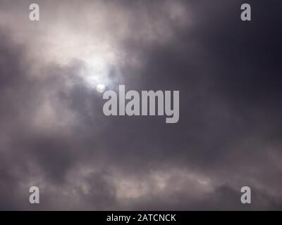 Die Sonne geht durch dunkle Wolken. Stockfoto