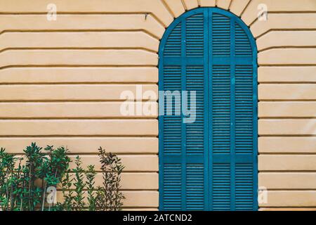 Gewölbte Tür in Blau an einer gelben Wand Stockfoto