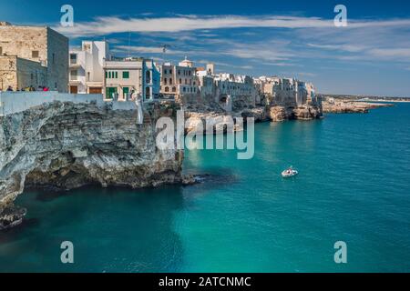 Häuser thront auf Felsen über Adria, Boot nähern Höhle, vom Largo Ardito Viewpoint, in Polignano a Mare, Apulien, Italien Stockfoto