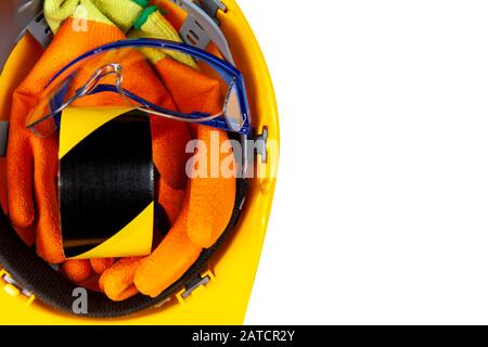 Hazzad-Klebeband, Arbeitshandschuhe und Sicherheitsblau umrandete Schutzbrille in einem gelben, auf einem rein weißen Hintergrund isolierten Hut Stockfoto