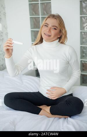 Glückliche Frau, Die Einen Schwangerschaftstest nach dem Ergebnis betrachtet. Stockfoto