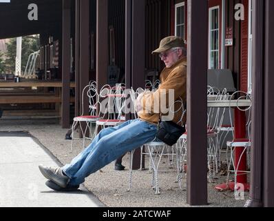 Mann, der draußen auf seine Frau wartet, um zu kaufen, an einem kalten Frühlingstag Stockfoto