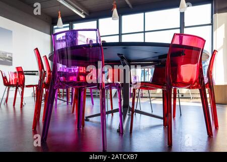 Low-Angle-Aufnahme eines Studienraums voller Tabellen Und bunte Stühle mit großen Fensterpaneelen Stockfoto
