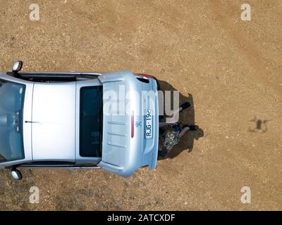 Luftaufnahme Mann sitzt fliegende Drohne zeigt Auto und Drohne Schatten, Victoria, Australien. Stockfoto
