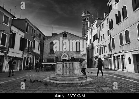 Venedig, ITALIEN - 20. Februar 2019: Ein Graustufenschuss von Menschen, die in der Nähe eines historischen Gebäudes in Venedig, Italien, spazieren Stockfoto