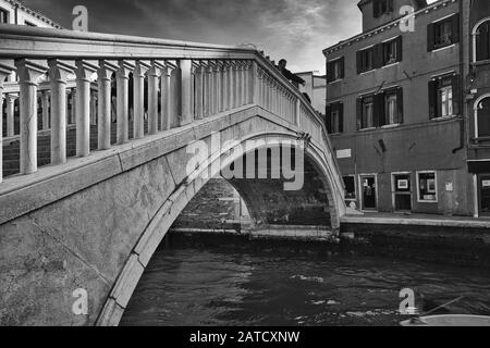 Venedig, ITALIEN - 20. Februar 2019: Ein Graustufenschuss einer historischen Betonbrücke über einen Fluss in Venedig, Italien Stockfoto