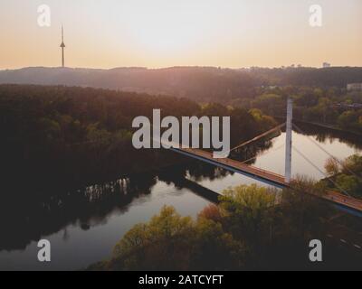 Brücke, die zwei Ufer des Flusses und einen Turm verbindet Im Hintergrund Stockfoto