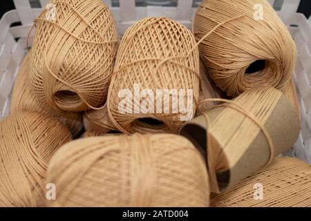 Set aus braunem Rollgarn in einem weißen Korb Stockfoto