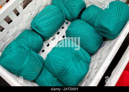 Set aus türkisfarbenen Garnen auf einem weißen Korb. Stockfoto