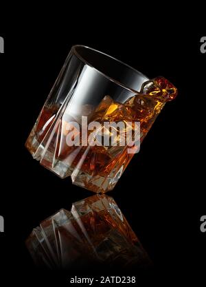 Splash Whisky mit Eiswürfel im Glas auf schwarzem Hintergrund Stockfoto