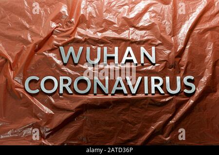 Wörter wuhan coronavirus gelegt mit Metallbuchstaben auf orange zerknittert Kunststoff-Folie Hintergrund - flach legen mit Komposition Stockfoto