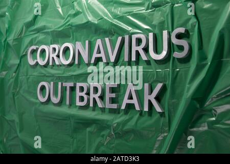 Die Worte Coronavirus Ausbruch gelegt mit silbernen Metallbuchstaben auf Grüne zerknitterte Kunststofffolie Stockfoto