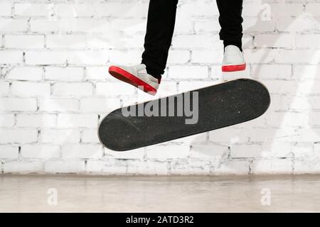 Skateboarder, der Skateboard-Trick ausführt - Kick Flip on Concrete. Olympiateilnehmer übt Sprung auf weißem Hintergrund und bereitet sich auf den Wettkampf vor. Extr Stockfoto