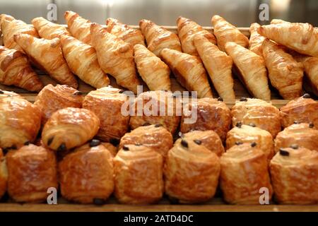 Gebackenes französisches Frühstücksgebäck für Gäste auf dem Hotelfrühstückstisch, goldbuttgebackene Schokolade und einfache Croissants in Reihen Stockfoto