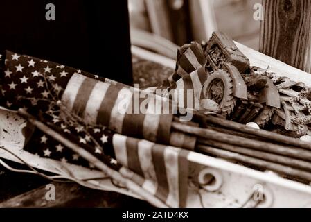 Traktor. Amerikanische Flagge. Ein Toy Farmall Traktor, mit einem Bündel gerollter US-Flaggen, auf einer Bank, hinter einem Sparladen, in Springfield, Georgia Stockfoto