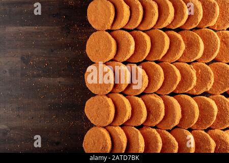 Gefrorene hamburger Teiglinge in Reihen auf einem hölzernen Tisch gestapelt, Ansicht von oben. Kopieren Sie Platz. Stockfoto
