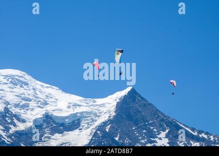 Gleitschirmflieger suchen Thermik unter den Schneekappen des Monte-Blanc-Massivs, Chamonix, Frankreich Stockfoto