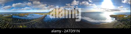 Epischer Luftdronblick an einem sonnigen Tag über die Landschaft des schwarzen Sandstrands in Stokksnes fliegen. Vestrahorn-Berg im Hintergrund. Natur und eg Stockfoto