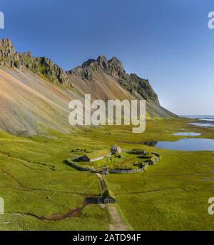 Isländische Luftlandschaften mit einem wikingerdorf in Stokksnes. Panorama auf den Vestrahorn-Berg an einem sonnigen Tag. Stockfoto